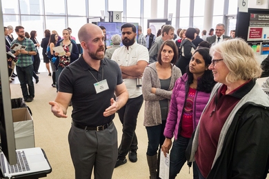 Attendees listening to a presenter at one of the poster session tables at Collaborating for MIT's Future.