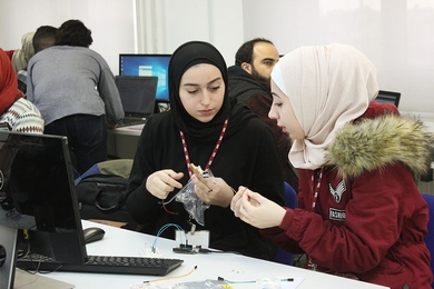 Students in the initial class examine electronics components as they begin their year-long course of studies.

