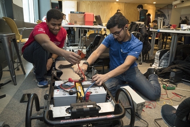MIT undergraduates Abdalla Osman (left) and Mohammed Nasir (right) work on optimizing a power soccer chair. 