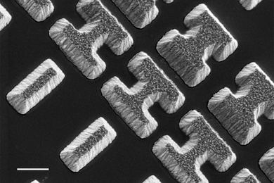 Scanning Electron Microscope image shows a few of the carefully designed shaped of the chalcogenide glass deposited on a clear substrate. The shapes, which the researchers call “meta-atoms,” determine how mid-infrared light is bent when passing through the material.