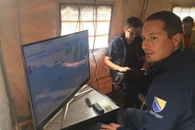 In the NICS command and control tent at the base of operations, Zeljko Sinkovic, who is working with the Laboratory to develop the Southeast Europe version of NICS, inputs information into the system. On the map, a car icon has been placed where responders have confirmed it has crashed, and the red dots represent the locations of responders.
