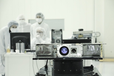 Members of the ASTERIA team prepare the petite satellite for its journey to space. 