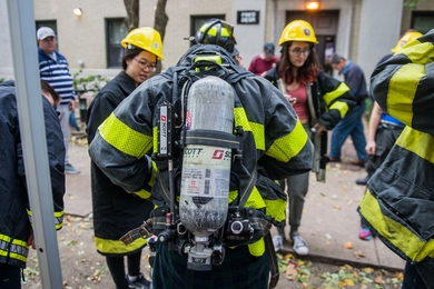 East Campus students try on firefighter gear, while Cambridge Fire Department members explain the gear’s purpose.