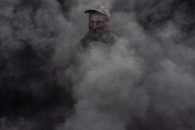 A worker at an outdoor quicklime kiln in the southeastern village of Kosturino, Macedonia. The operation burns tires for fuel.