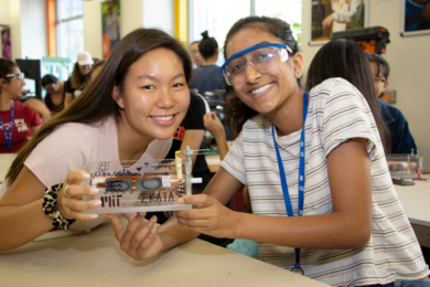 High school teammates display the DC motor they made before a Dustbusting by Design spin-off competition at MIT. The event is the culmination of the MRL MRSEC / EECS summer Women’s Technology Program.