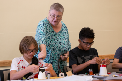 Susan Rosevear (center), education officer for MIT Materials Research Laboratory’s Materials Research Science and Engineering Center, instructs students from the Putnam Avenue Upper School in Cambridge, Massachusetts, how to build a simple direct current (DC) motor.