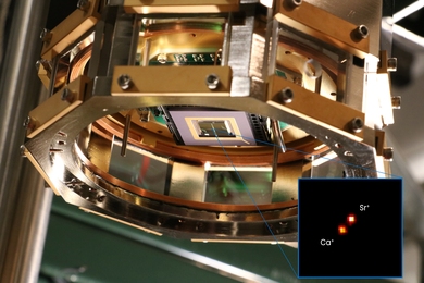 An ion-trap chip (at center) is used to hold two calcium and strontium ions still as the qubits they house become entangled. The inset shows a magnified, false-color image of light scattering from each ion in the trap as they are laser cooled.