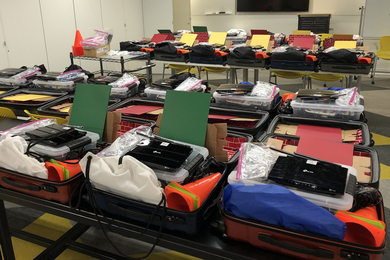 About 30 RACECAR model kits on tables in an otherwise emtpy classroom
