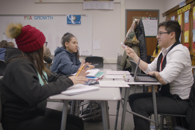 Photo of two students at a desk with a tutor