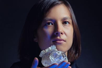 Photo of Helen Schwerdt holding a plastic model of a brain region with half a dozen needlelike probes sticking out