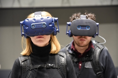 Photo of a woman and a man wearing VR headsets and suits 