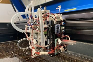 Photo of a small (~foot-wide) device bristling with wires, tubes, and computer chips