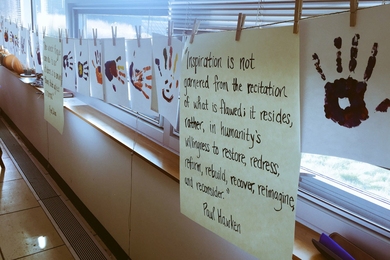 Photo of multicolored handprints hanging from a clothesline with an inspirational quote. 