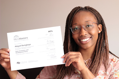Photo of a woman smiling at the camera, holding MITx MicroMasters completion certificate