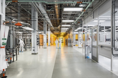 Photo of several people in cleansuits walking through MIT.nano