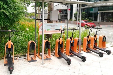 Photo of black e-scooters docked at an orange sharing service station in Singapore.