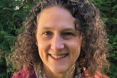 Portrait photo of Arlene Fiore, smiling, with foliage in the background