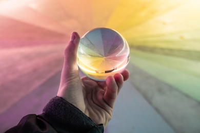 Photo of a hand holding a crystal ball with color perspective behind