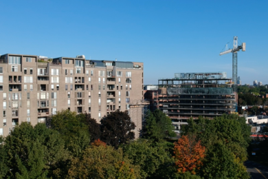 Photo of a concrete apartment complex next to the skeleton of an office building under construction