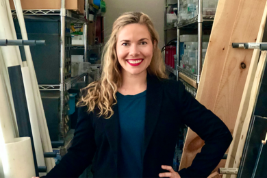 Photo of Ana Pantelic posing, smiling, in front of shelves full of boxes and equipment