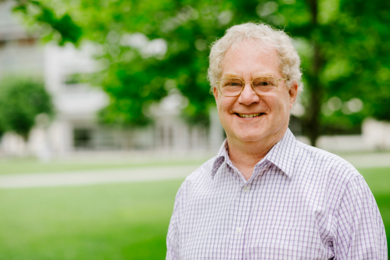 Portrait photo of Alan Grossman standing in Hockfield Court, with trees and a building in the background