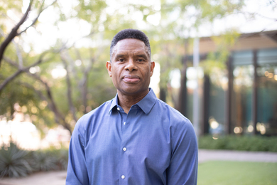 Photo of S. Craig Watkins standing outside, in front of a tree and a building