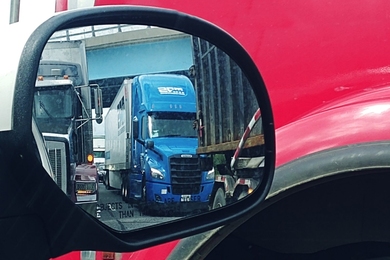 Stock photo of trucks reflected in an automobile mirror