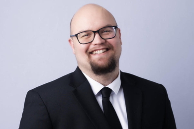 Headshot of Michael Pilgreen, smiling and wearing a coat and tie