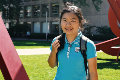 Photo of Sherry Nyeo outdoors on MIT's Hockfield Court, with a red sculpture and an MIT building behind her