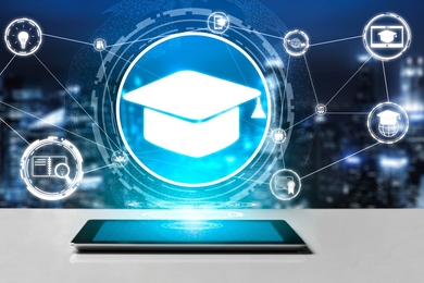 Abstract image of a phone laying flat on a table, with a hologram of a graduation cap with icons representing education connected by lines hovering over it. 