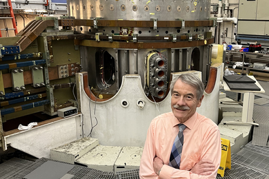 Ian Hutchinson stands in the Alcator C-Mod tokamak cell at MIT with the tokamak in the background.