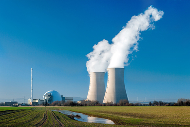 A nuclear plant next to a grass field and pond is pictured.