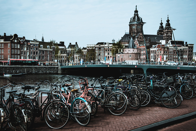 Rows of bikes are parked near a canal in beautiful Amsterdam.