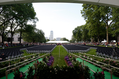 Photo of MIT's Killian Court, facing Boston, featuring hundreds of empty seats meant for new graduates, while spectators stand in the background