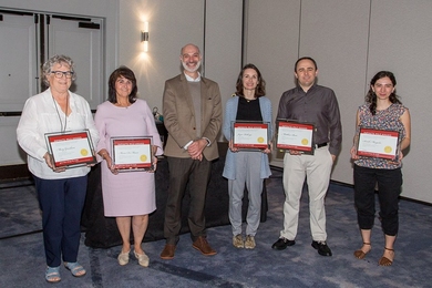 Agustin Rayo stands with five winners of the 2023 Infinite Mile Awards, each of them holding up their plaque for the camera