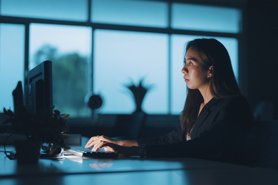 A woman working at a computer while sitting at desk.