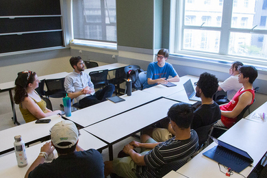 Six students and Associate Professor Justin Khoo sit around a table and listen as Quincy Cantu speaks.
