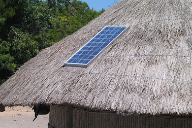A single solar panel is installed on a thatched roof