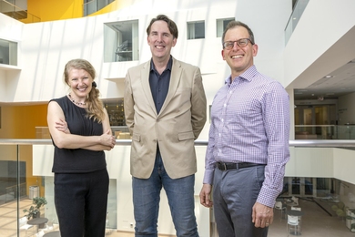 Ev Fedorenko, Edward "Ted" Gibson, and Roger Levy pose together, standing on a walkway overlooking an atrium