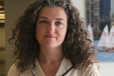 Lerna Ekmekciouglu in front of a window with sailboats on the Charles River in the background. 