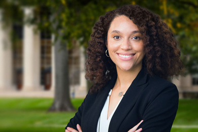 Headshot of Sydney Johnson as seen in front of MIT Building 10 columns and trees of Killian Court