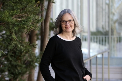 Heather Paxson leans on a railing and smiles for the camera.