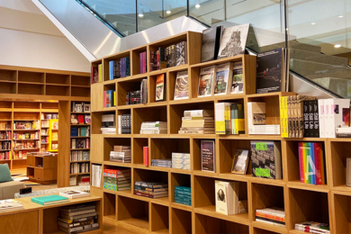 Photo of MIT Press Book Store shelves nestled beneath a glass stairwell