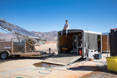 In rural New Mexico, a solar panel truck is next to a trailer with lots of hoses connected to it going many directions.