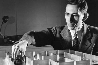 Black and white photo of Claude Shannon with his desktop mouse maze