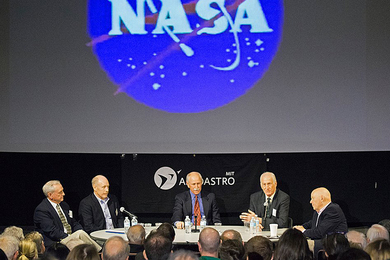 Tom Akers, Ken Bowersox, Dick Covey, Jeff Hoffman, and Story Musgrave speak on a panel in front of a screen with the NASA "meatball" logo