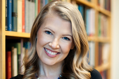 Portrait of smiling woman in front of bookshelves. 