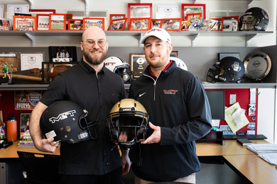 Kodiak Brush and Brian Bubna hold football helmets