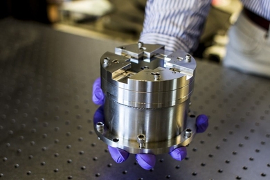 Hand in purple latex gloves holds a cylindrical metal device.