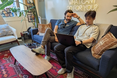 Alex Shalek and Bokai Zhu look at a laptop while sitting on a sofa in an office.